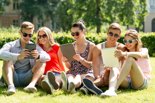 smiling friends with tablet pc computers in park - 写真・画像