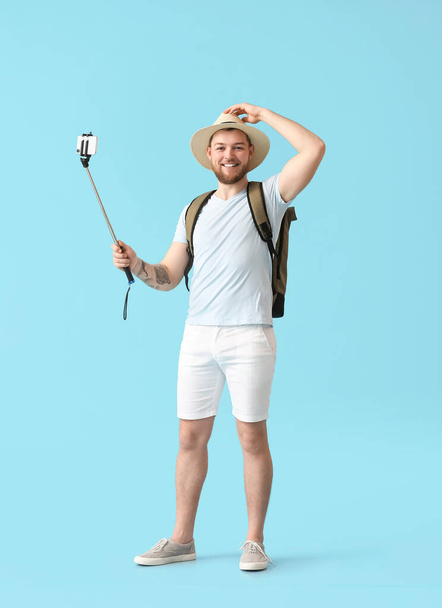 Male tourist taking selfie on color background - Фото, изображение