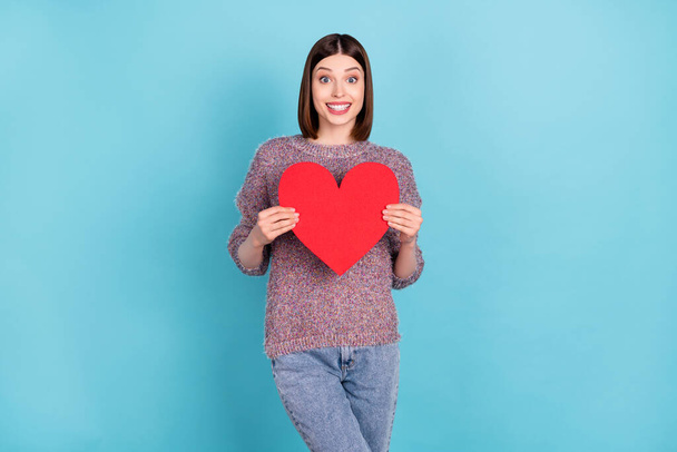 Photo of excited girlfriend lady hold red paper heart card wear knitted pullover isolated blue color background - Foto, imagen