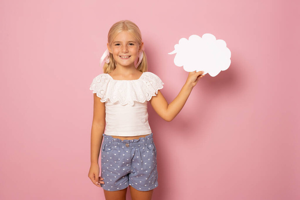 Portrait of cheerful girl holding paper cloud copy space isolated over pink background - Valokuva, kuva