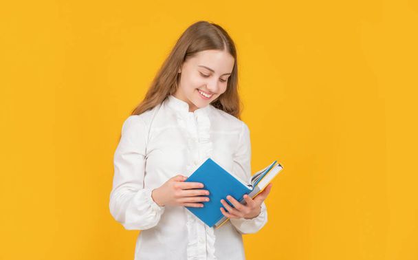 feliz adolescente chica en camisa blanca listo para estudiar hacer la tarea leer libro sobre fondo amarillo, lector - Foto, imagen