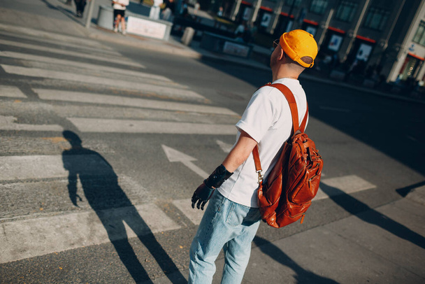 Fiatal fogyatékos férfi mesterséges protézis kéz alkalmi ruhák és hátizsák séta napos város utcán szabadban - Fotó, kép