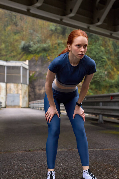 Motivated and focused woman before run on walkway bridge. Female athlete outdoors - Fotó, kép