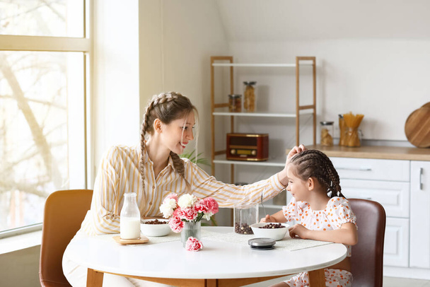 Маленькая девочка и ее мать завтракают на кухне - Фото, изображение