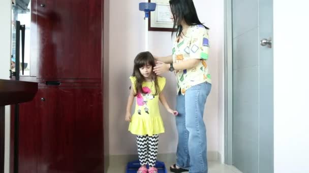 Médico mide crecimiento sonriente chica en el consultorio médico
 - Metraje, vídeo