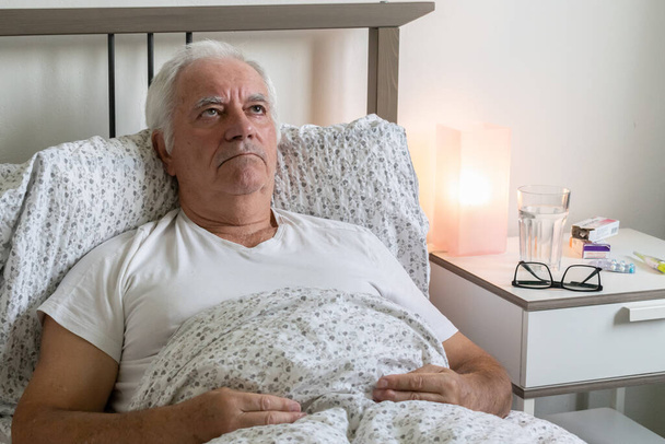 alternder älterer älterer Mann Mann im Bett zu Hause Wohnung müde krank krank allein Rentner Ruhe Virus Pflege unglücklich traurig - Foto, Bild