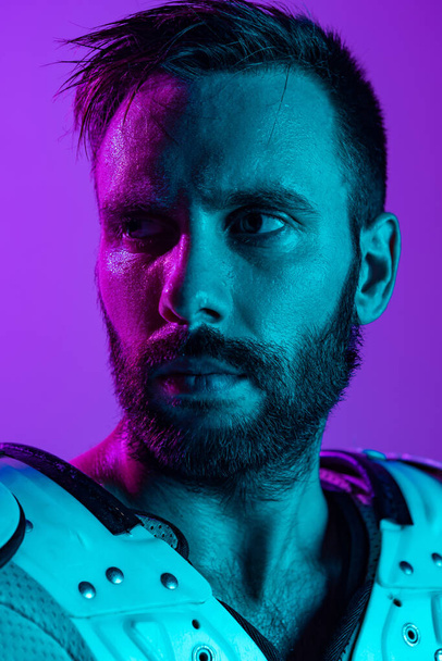 Retrato de primer plano de jugador de fútbol americano masculino aislado sobre fondo púrpura estudio en neón - Foto, imagen
