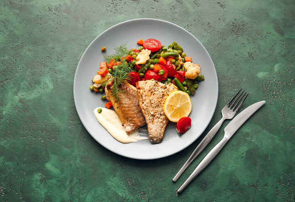 Plate with tasty baked cod fillet, vegetables and sauce on color background - Foto, Imagen