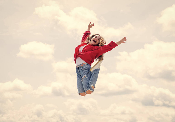kid jump outdoor. kid fashion and beauty. sense of freedom. portrait of energetic child girl. concept of future. happy childhood. cheerful teen girl jumping high - Photo, Image