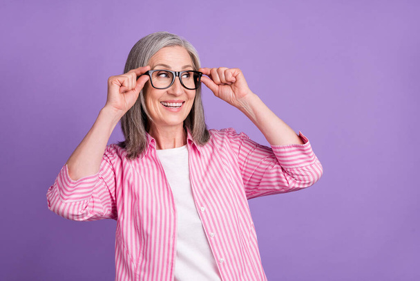 Profile side photo of aged woman happy positive smile look empty space wear eyeglasses isolated over purple color background - Foto, immagini