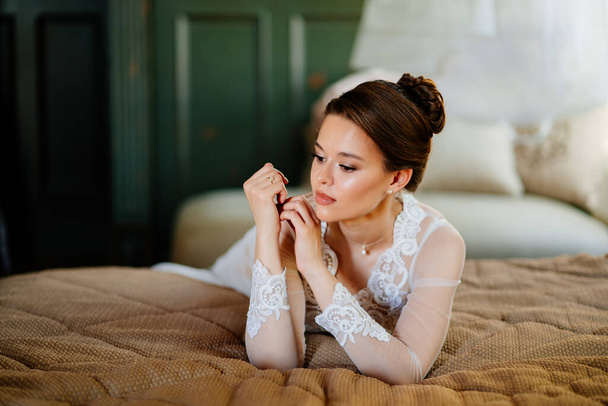 a brunette bride in a lace robe lies in bed. morning before the wedding. - Foto, imagen