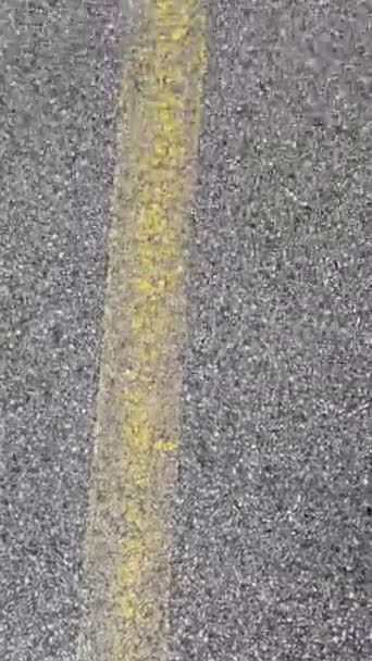 Wandelen langs de gele lijn op het asfalt. Hand vast, hoge pief. Je kunt de schoenen zien.. - Video