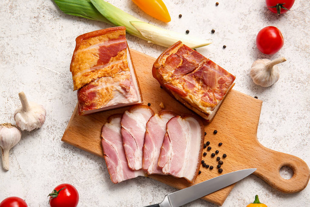 Wooden board with tasty smoked bacon and fresh vegetables on light background - Fotoğraf, Görsel