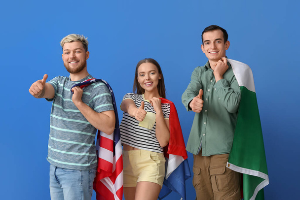 Young people with different flags showing thumb-up on color background - Фото, изображение