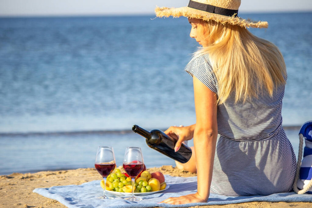 Beautiful smiling woman with a glass of wine on the beach. Fruit red wine. Selective focus. - Foto, Imagen