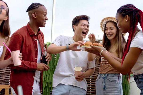 Grupo de amigos positivos diversos que se divierten en la fiesta de barbacoa al aire libre en el patio trasero - Foto, imagen