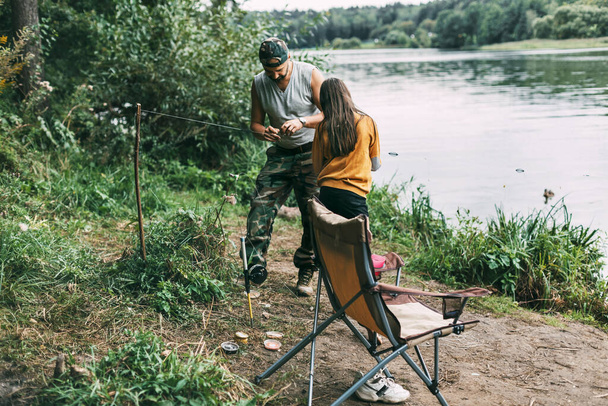 Батько вчить свою дочку-підлітка ловити рибу під час сімейної відпустки
 - Фото, зображення