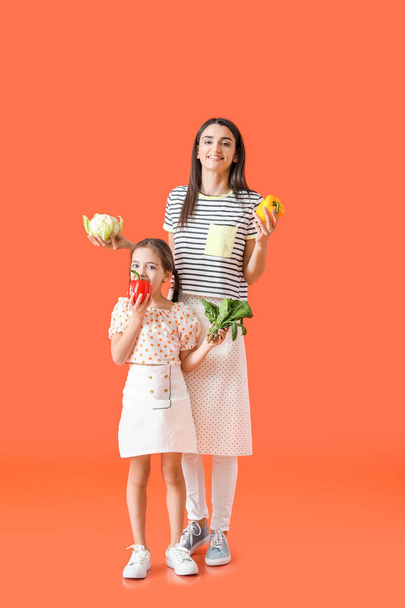 Young mother and daughter with tasty vegetables on color background - Photo, Image