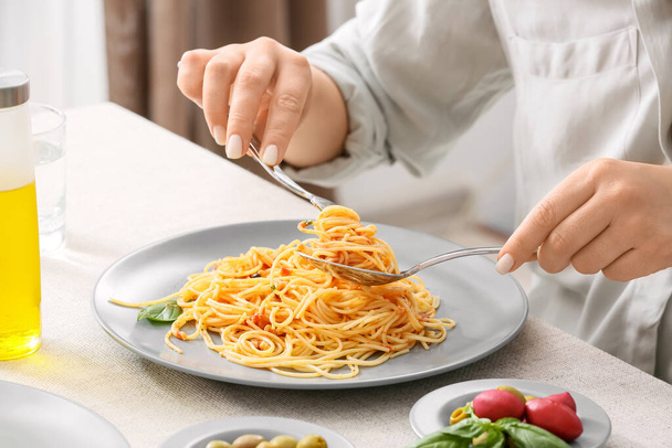 Mujer comiendo sabrosa Pasta Puttanesca a la mesa en restaurante, primer plano - Foto, Imagen