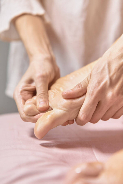 Közelítse meg a reflexológia lábmasszázst. Profi terapeuta, aki láb- és lábmasszázst ad egy nőnek a gyógyfürdőben. Női masszázs terapeuta masszírozza az ügyfelek lábát. Testrelaxáció és bőrápolás - Fotó, kép