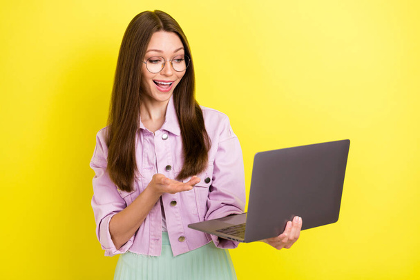 Photo of pretty brunette hairdo young lady talk laptop wear spectacles pink shirt isolated on yellow color background - Fotografie, Obrázek