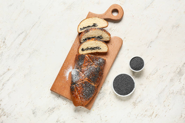 Placa de madeira com pão de semente de papoila fatiado e ingredientes em fundo claro - Foto, Imagem