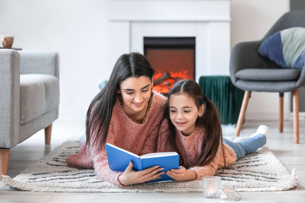 若いです母とともに娘読書本近く暖炉に自宅 - 写真・画像