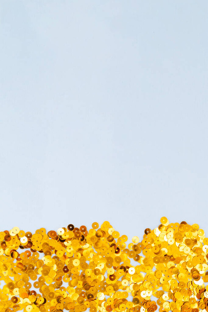 Lichtblauwe achtergrond met gouden confetti, selectieve focus - Foto, afbeelding