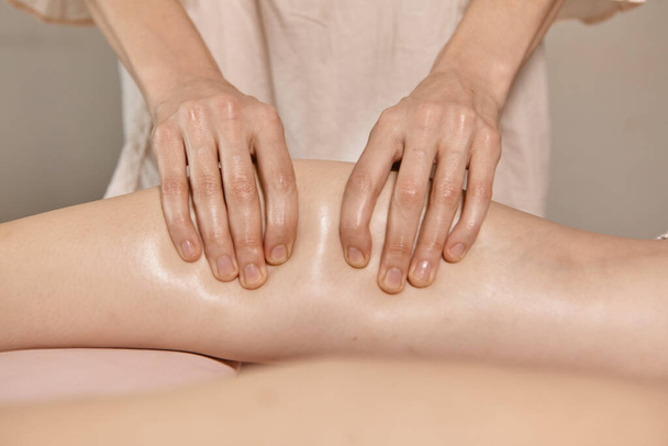 Close up reflexologia massagem nos pés. Terapeuta profissional dando massagem muscular na panturrilha para uma mulher no spa. Massagista feminina massagista clientes pernas. Relaxamento corporal e cuidados com a pele - Foto, Imagem