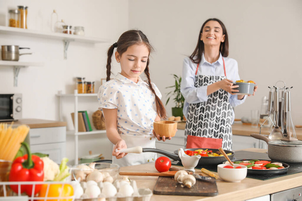 Bambina con mamma che cucina in cucina a casa - Foto, immagini