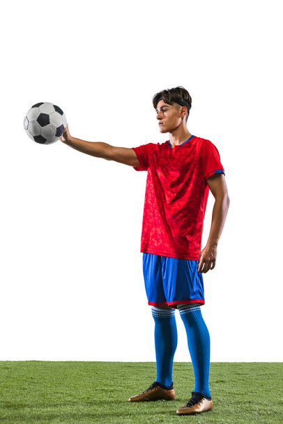 Full-length portrait of young male soccer football player holding ball with one hand isolated over white background. - Photo, Image