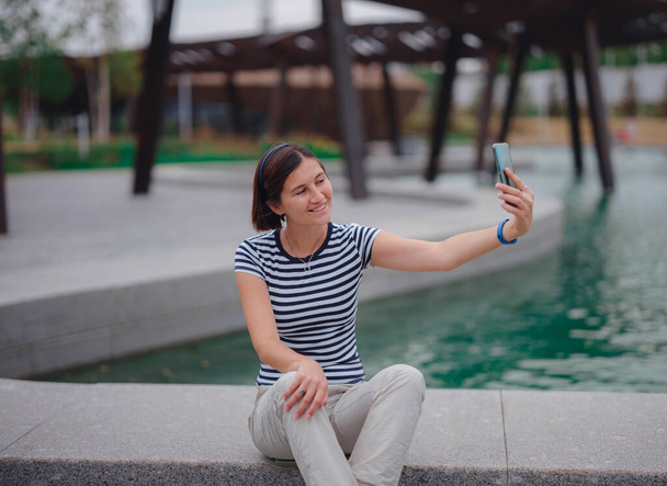 Portrét krásné asijské mladé ženy selfie v parku s chytrým telefonem nebo dělat videokall s přáteli. koncept sociálních sítí - Fotografie, Obrázek