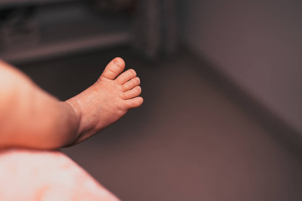 ベッドに横たわっている間に認識できないかわいい赤ちゃんの足のクローズアップ、無邪気なコンセプト - 写真・画像