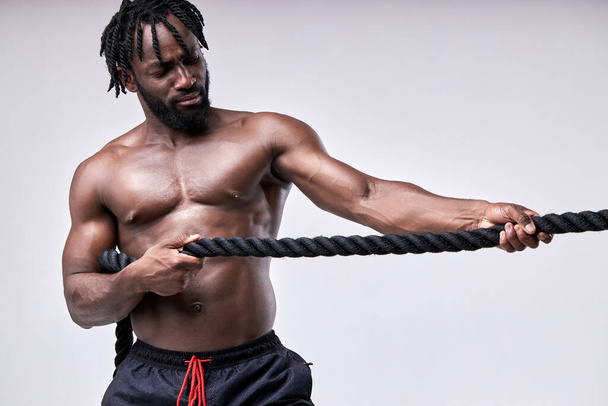 confident african american athlete pulling cross fit rope isolated on white background - 写真・画像