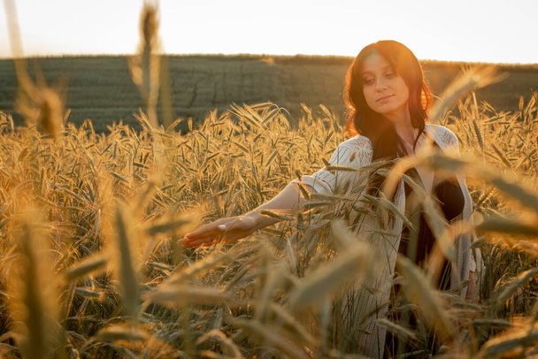 coucher de soleil, couleurs douces du soir, jeune, belle, fille brune émotionnelle aux cheveux longs sur un champ de blé, d'or. Calme, réconfort dans l'âme - Photo, image
