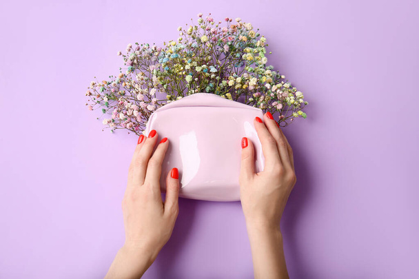Woman with beautiful manicure holding cosmetic bag with flowers on color background - Fotografie, Obrázek