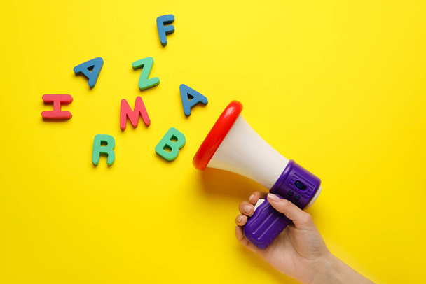 Γυναίκα με μεγάφωνο παιχνίδι και γράμματα στο φόντο χρώμα - Φωτογραφία, εικόνα