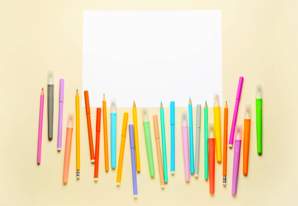 Marqueurs colorés, crayons et feuille de papier vierge sur fond de couleur - Photo, image