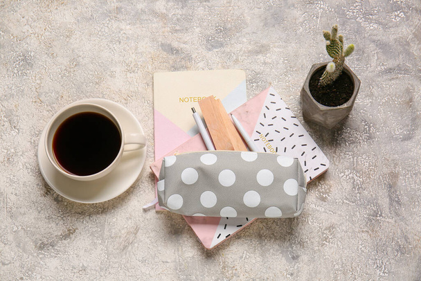 Stylish pencil case with stationery and cup of coffee on grunge background - Foto, imagen