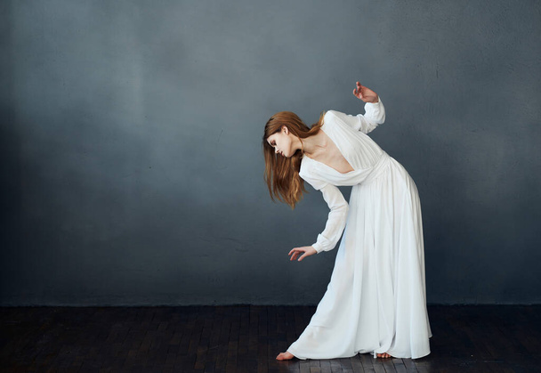 Woman in white dress dance movement performing dark background - Photo, image