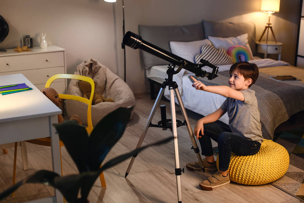 Мальчик смотрит на звезды через телескоп вечером - Фото, изображение