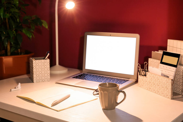 Σύγχρονη χώρο εργασίας με υπολογιστή και λαμπερό φως κοντά στον τοίχο χρώμα - Φωτογραφία, εικόνα