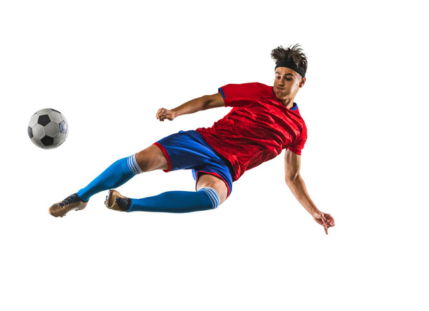 Full-length horizontal portrait of young man, soccer football player training isolated on white background. In a jump - Photo, Image