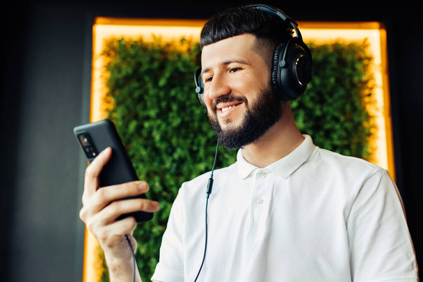 Business video conferencing, Young man with headphones having a video call via mobile phone at home, Virtual home party, Online team meeting, video conferencing, call from home - 写真・画像