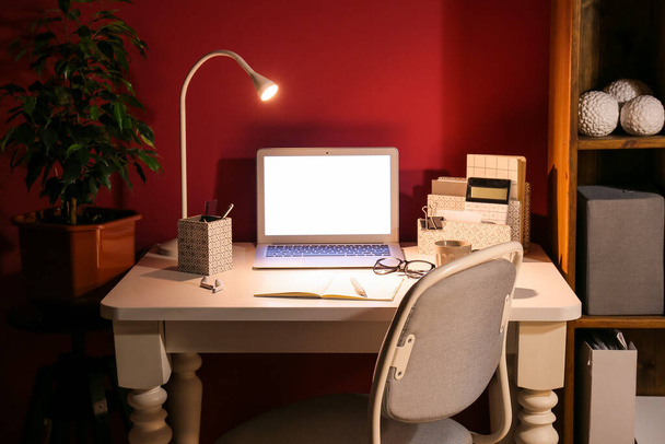 コンピューターとカラーウォールの近くに光るランプの現代的な職場 - 写真・画像