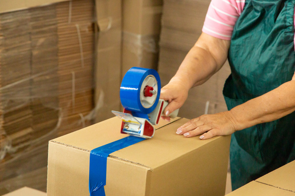 Mujer en almacén trabajador uniforme embalaje caja de cartón a la entrega. - Foto, Imagen