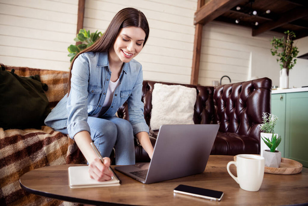 Foto van gelukkig mooie jonge vrouw schrijven briefje lopen laptop glimlach goed humeur binnen huis binnen huis - Foto, afbeelding