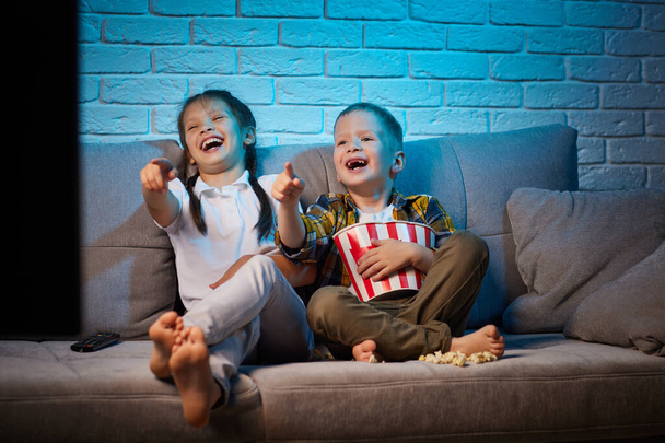 twee kinderen met afstandsbediening tv kijken - Foto, afbeelding