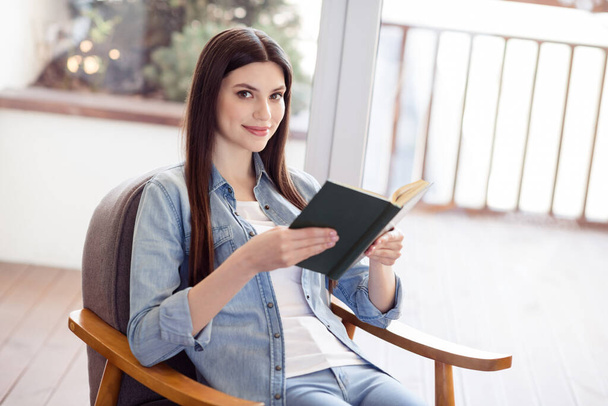 Photo attractive young joyful woman sit chair read book hobby good mood indoors inside house home flat - Photo, image