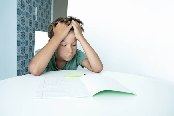 El chico triste con libro hace los deberes escolares. De vuelta a la escuela. Escolar infeliz con libros de texto. Aprendizaje a distancia - Foto, Imagen